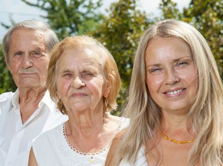 Three elderly individuals standing side by side, smiling.