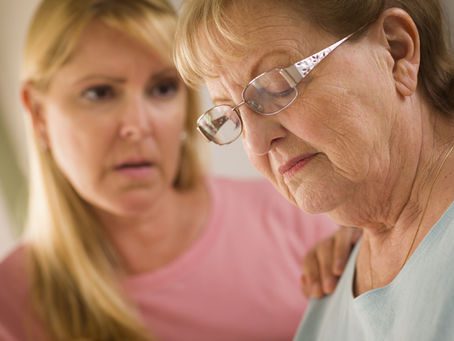 A young woman gazes at an elderly woman with a smile, showing love and respect between generations.